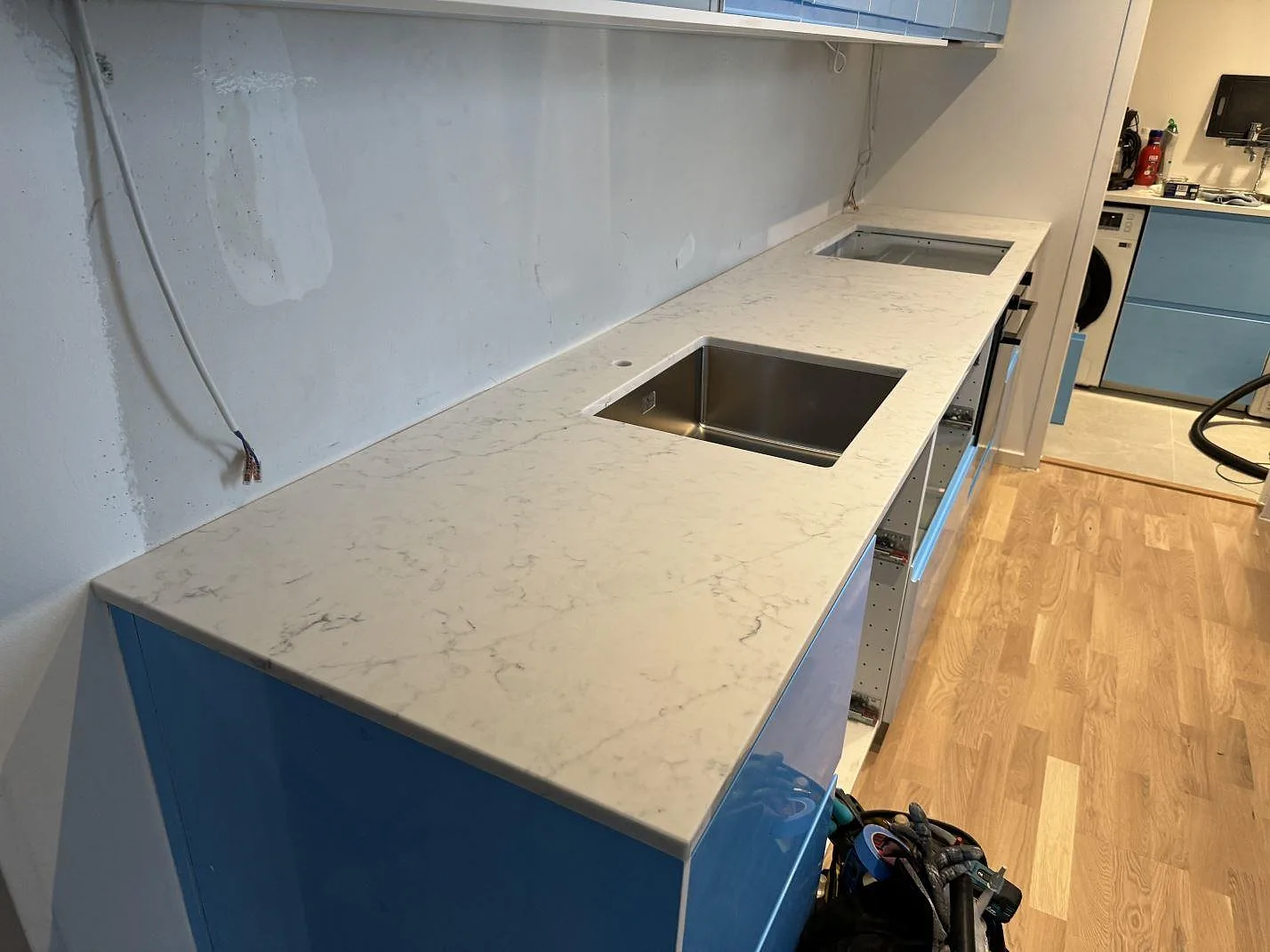 Köksbänkskiva i vit Technistone Mystery White, polerad komposit, med underlimmad rostfri diskho och hällöppning i ett kök i Malmö.