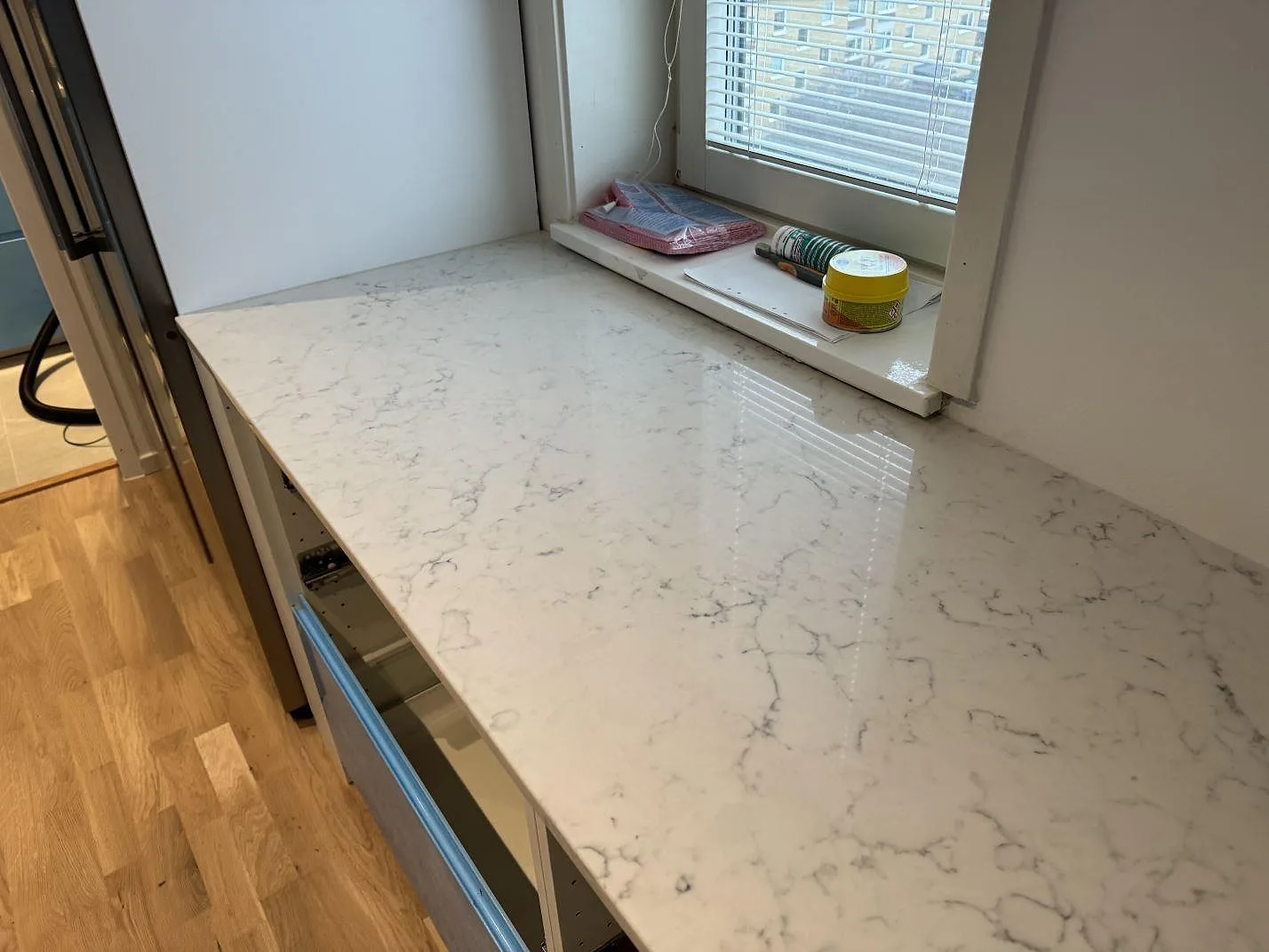 Närbild av vit kompositbänkskiva i Technistone Mystery White med grå ådring och blank polerad yta vid ett köksfönster i Malmö.