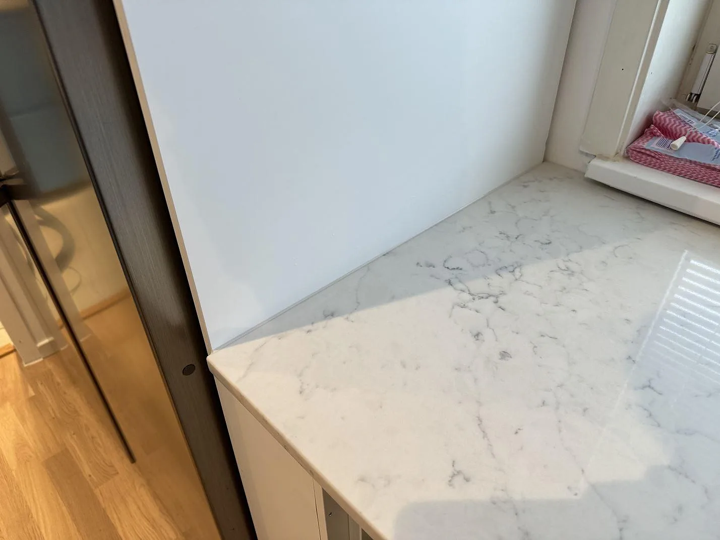 Närbild av blank Technistone Mystery White som köksbänkskiva med grå ådring vid fönsterdelen i Malmö.