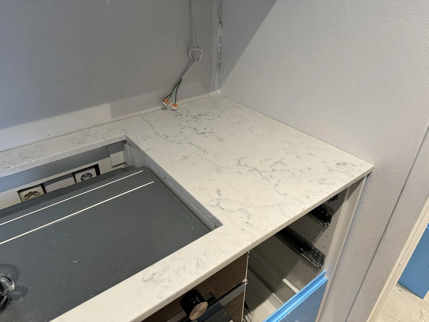 Detalj av Technistone Mystery White i polerad komposit runt hällöppning och bänkyta under köksmontering i Malmö.