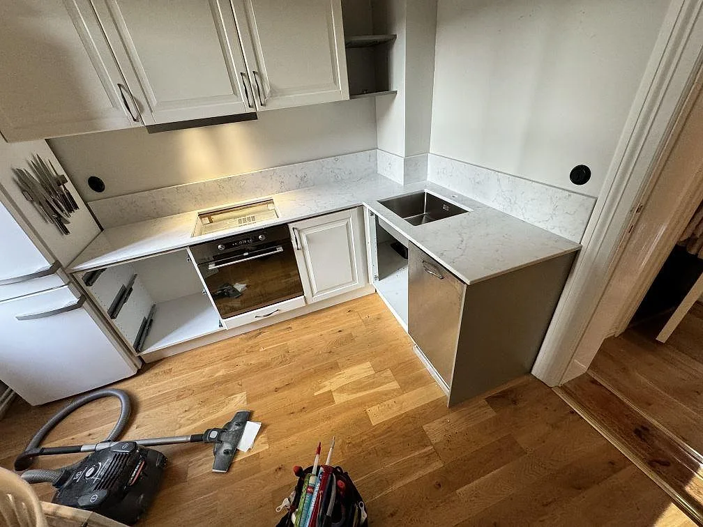 L-format kök i Malmö med polerad Technistone Mystery White som köksbänkskiva, uppvikt stänkskydd, underlimmad rostfri diskho och öppning för downdraft-häll.