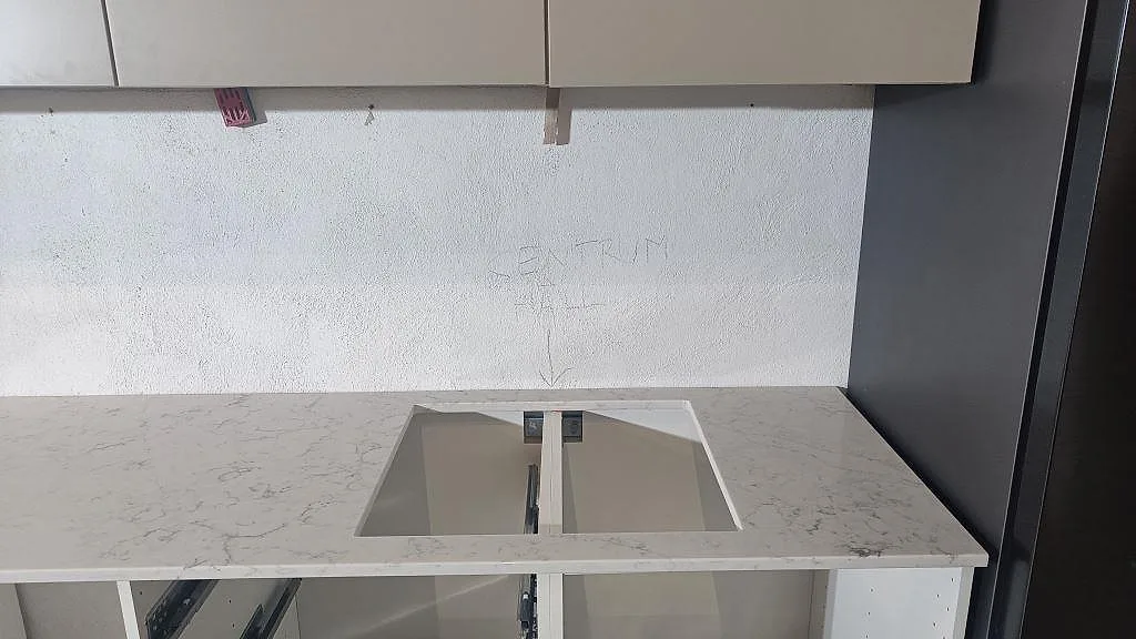 Höger del av köksbänkskiva i Technistone Mystery White, polerad kvartskomposit, med utskärning i arbetsytan vid högskåp i Malmö.