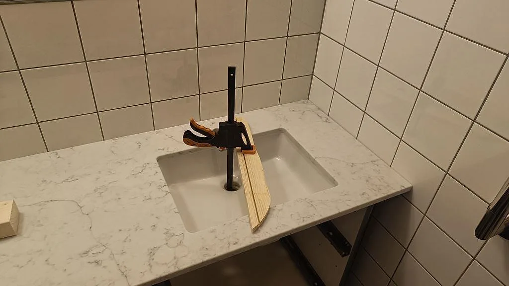 Höger tvättställ i en polerad badrumsbänkskiva av Technistone Mystery White komposit, monterad mot kaklade väggar i Malmö.