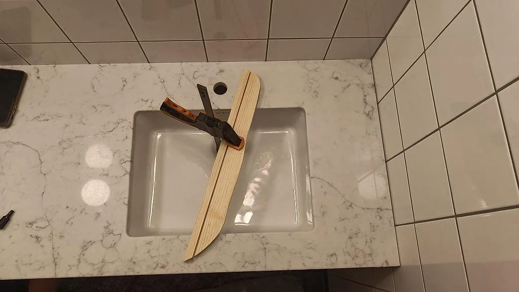 Detalj av polerad Technistone Mystery White-bänkskiva i badrum med synligt tvättställ, blandarhål och ljus grå ådring i Malmö.