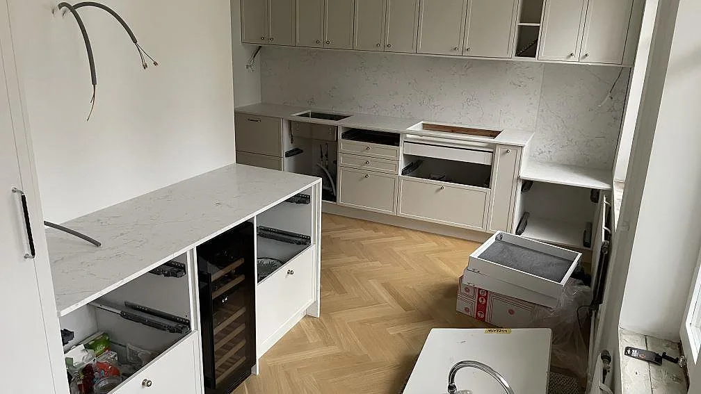 Köksbänkskivor i polerad Technistone Mystery White, vit kvartskomposit, med fristående bänkyta och matchande väggbeklädnad i ett kök i Malmö.