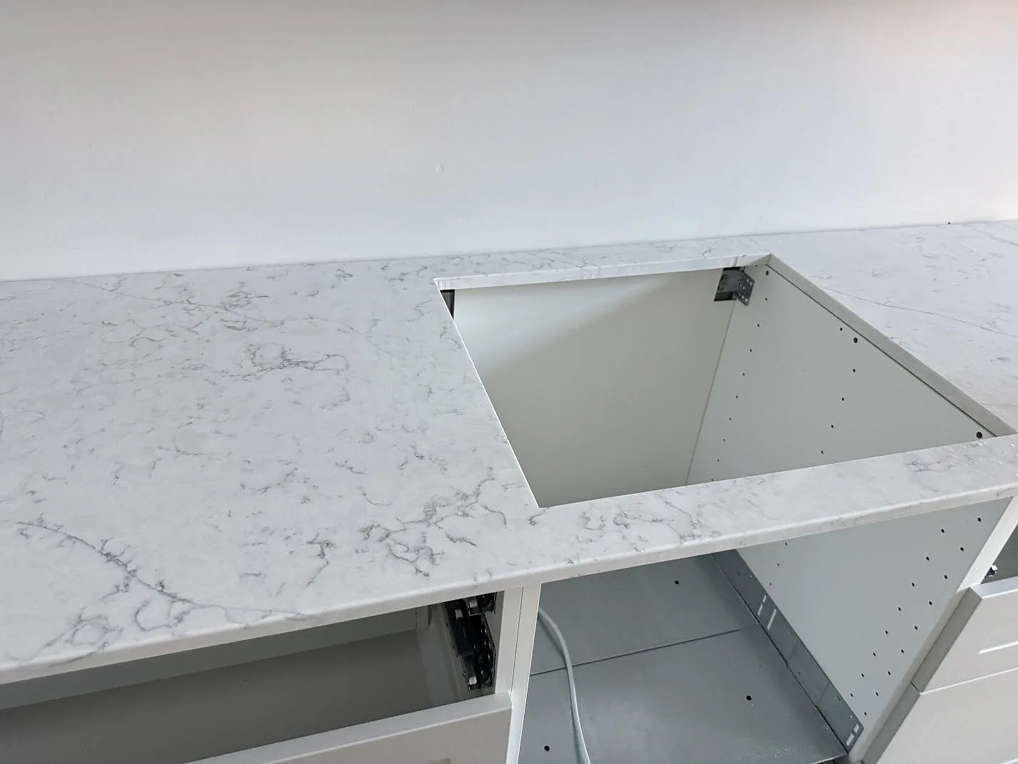 Förberedd diskhoöppning i köksbänkskiva av polerad Technistone Mystery White under montering i Malmö.