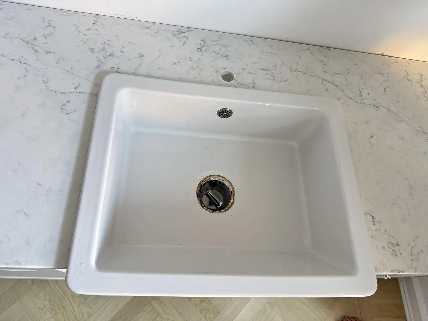Ovanifrån på vit diskho och polerad Technistone Mystery White med runt blandarhål och grå ådring i Malmö.