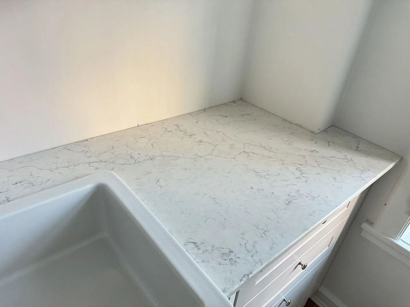 Höger arbetsyta i polerad Technistone Mystery White vid vit diskho och fönster, monterad på ljusa köksstommar i Malmö.