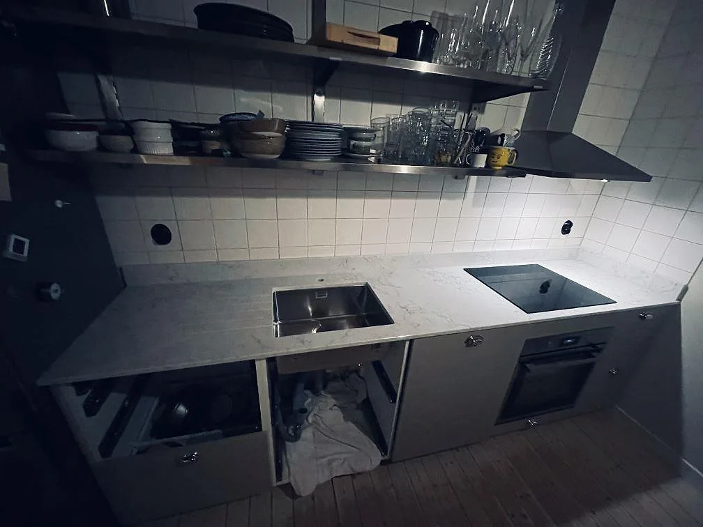 Köksbänkskiva i vit Technistone Mystery White, polerad kvartskomposit med grå ådring, med underlimmad rostfri diskho och infälld induktionshäll i ett kök i Malmö.