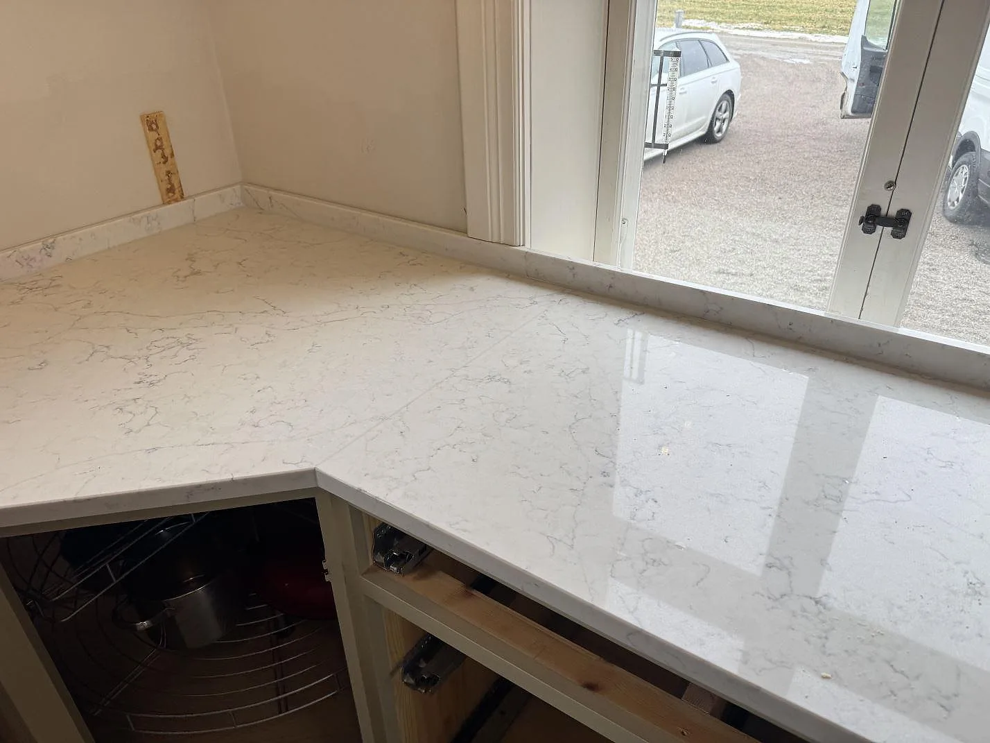 Hörn av köksbänkskiva i Technistone Mystery White med uppvikt stänkkant i samma vita kvartskomposit i ett kök i Näsum.