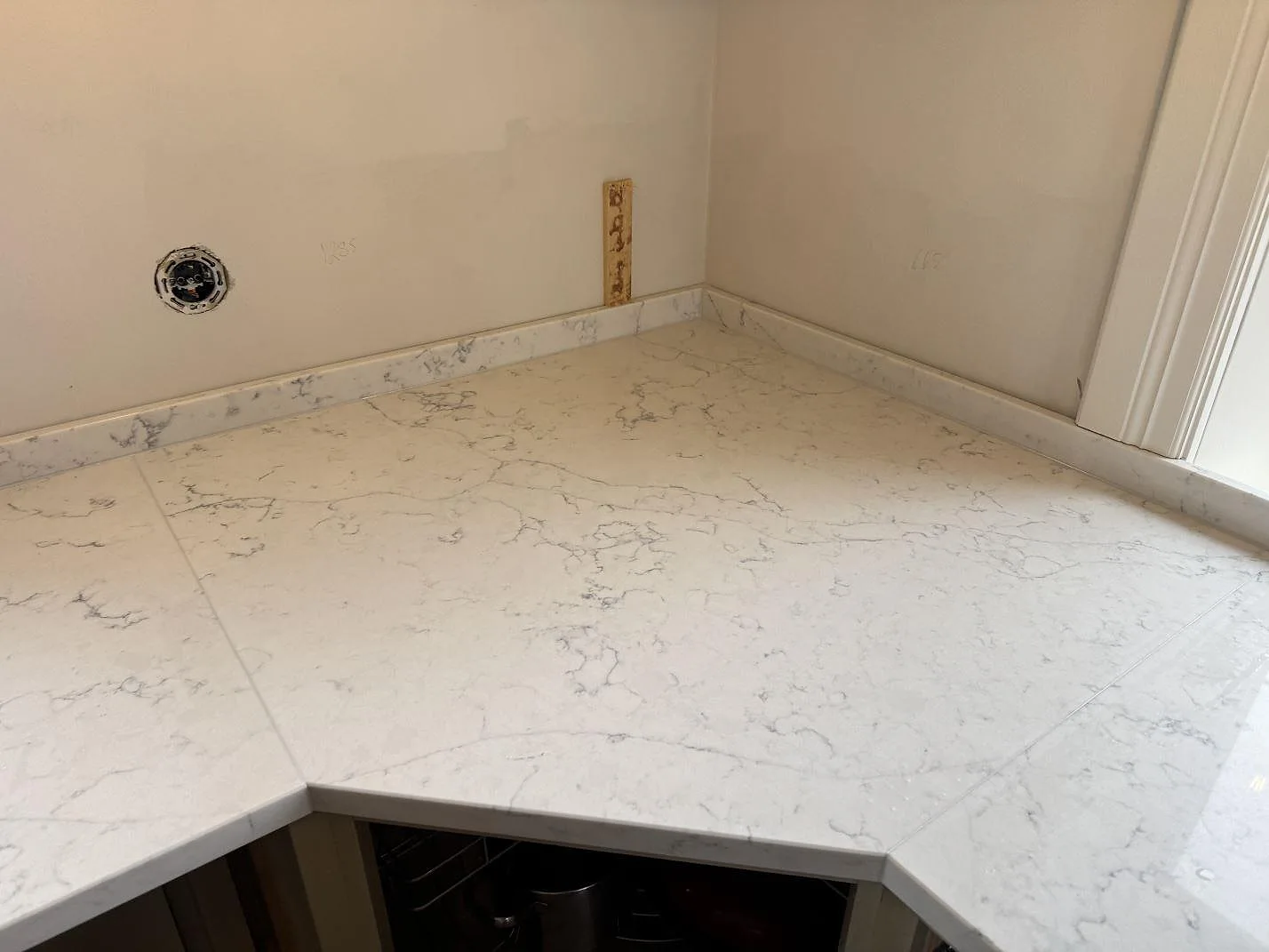 Nedifrån ovansett vinkel på köksbänkskivan i vit Technistone Mystery White med tydlig grå marmorådring i ett kök i Näsum.
