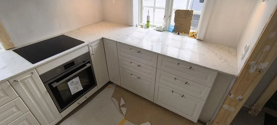 Köksbänkskiva i Technistone Mystery White, polerad kvartskomposit, vid häll och lång fönsteryta i Norrtälje Rö.