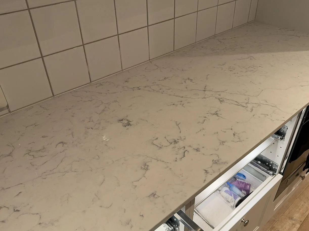 Närbild på den polerade ytan i Technistone Mystery White komposit med ljus botten och grå ådring i Nyehusen.