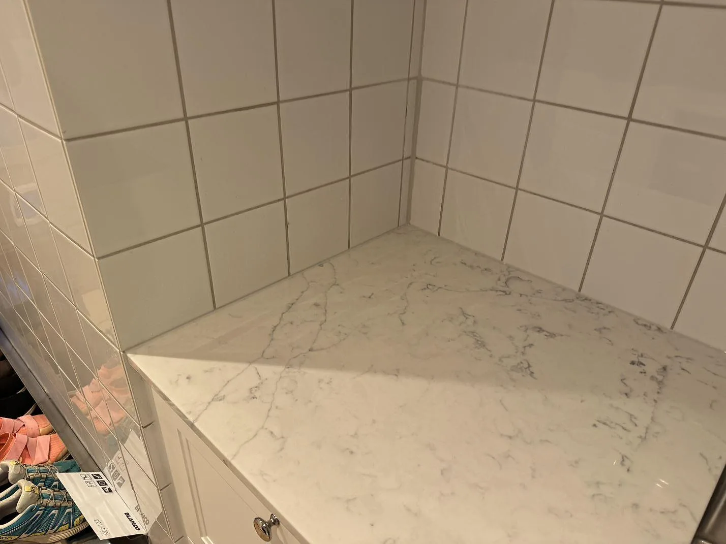 Hörnparti av köksbänkskiva i Technistone Mystery White, polerad komposit med grå ådring, under montering i Nyehusen.
