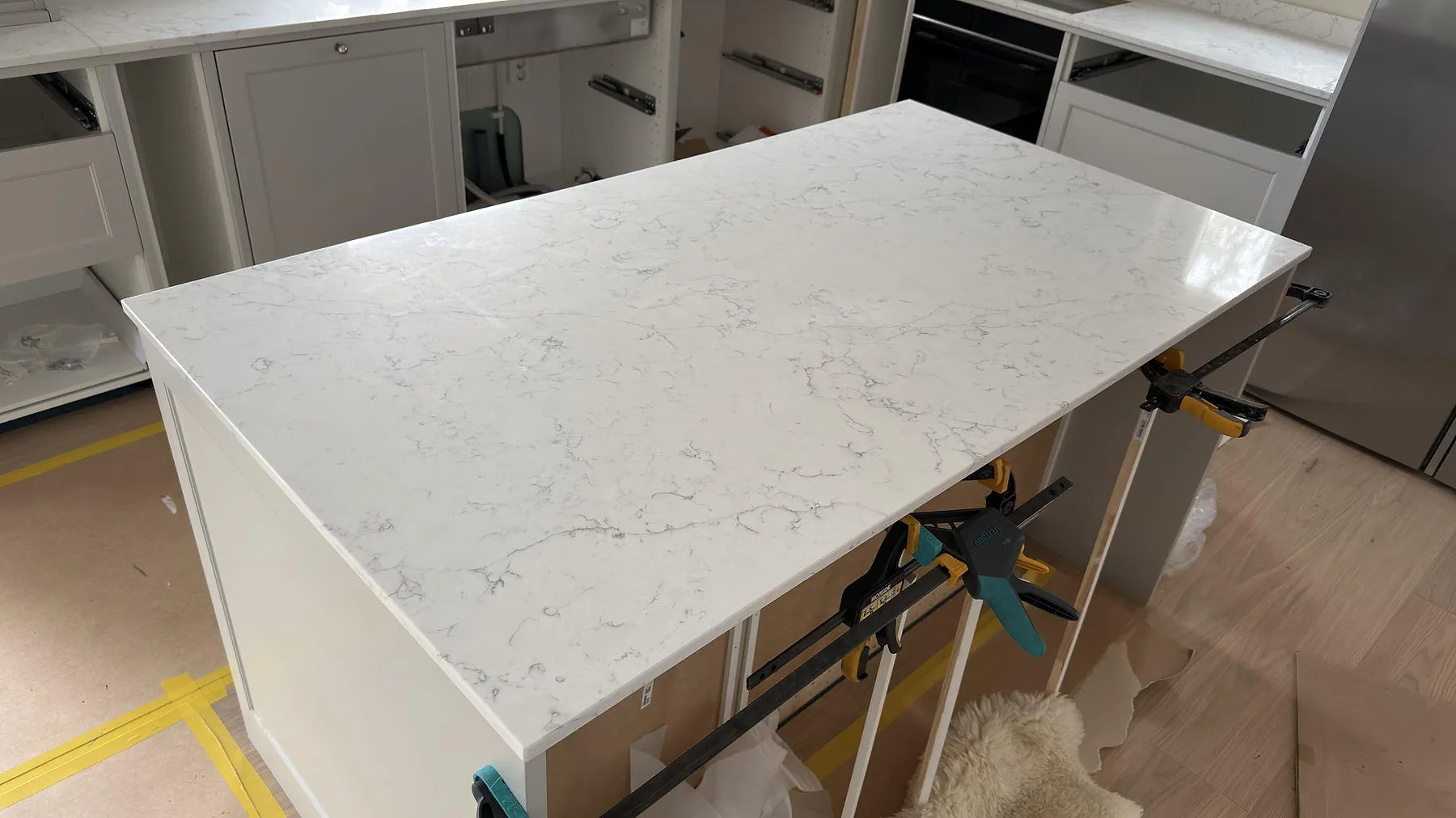 Närbild på köksö i polerad Technistone Mystery White kvartskomposit med ljus botten och grå ådring i Örebro.