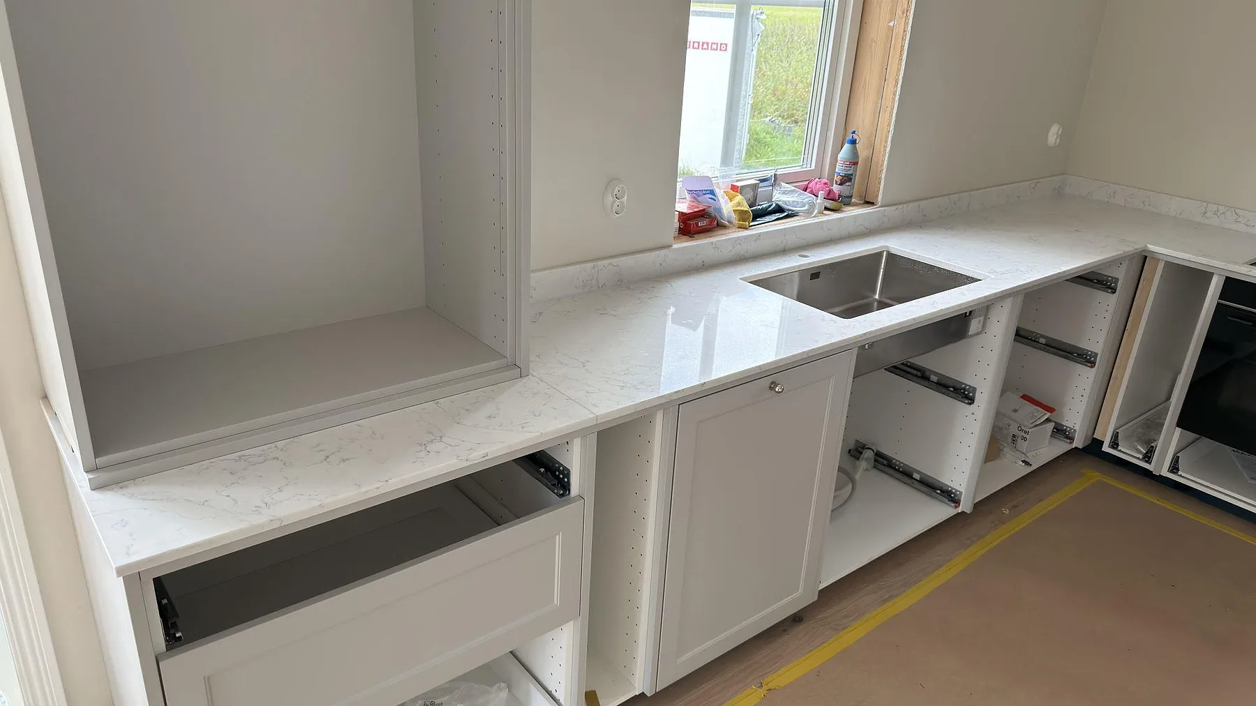 Köksbänkskiva i Technistone Mystery White kvartskomposit med rostfri diskho och låg stänkkant vid fönster i Örebro.
