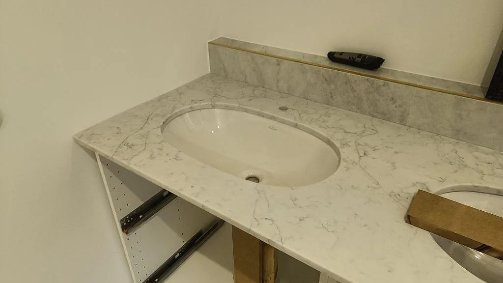 Närbild av polerad Technistone Mystery White komposit runt ett ovalt tvättställ i badrum i Råå.