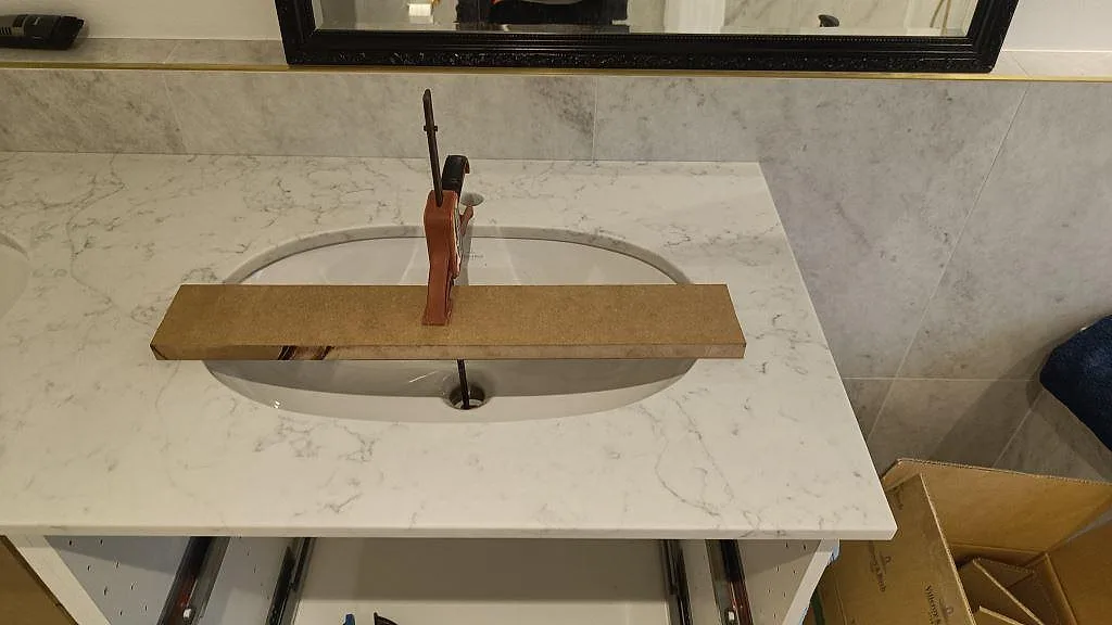 Högersidan av badrumsbänkskiva i polerad Technistone Mystery White komposit med tvättställ och grå ådring i Råå.