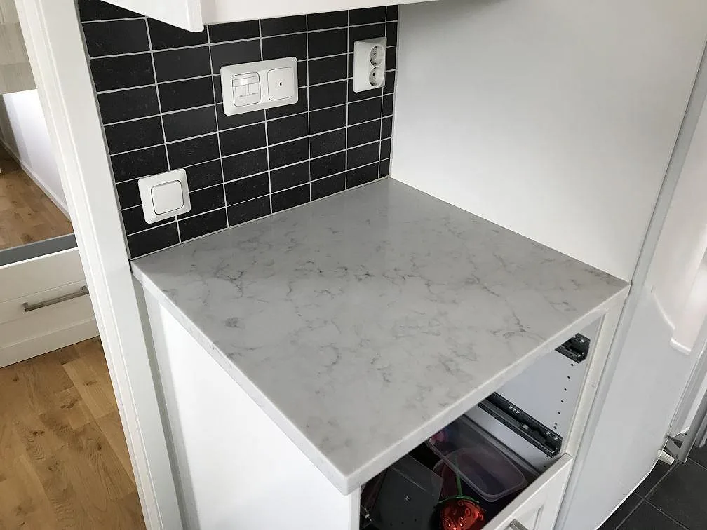 Polerad Technistone Mystery White köksbänkskiva mot svart kakel ovanför öppna köksstommar i Rydebäck.