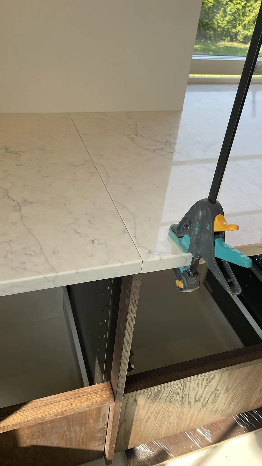 Skarvdetalj i polerad Technistone Mystery White komposit under montering med tving på bänkskivan i Rydsgård.
