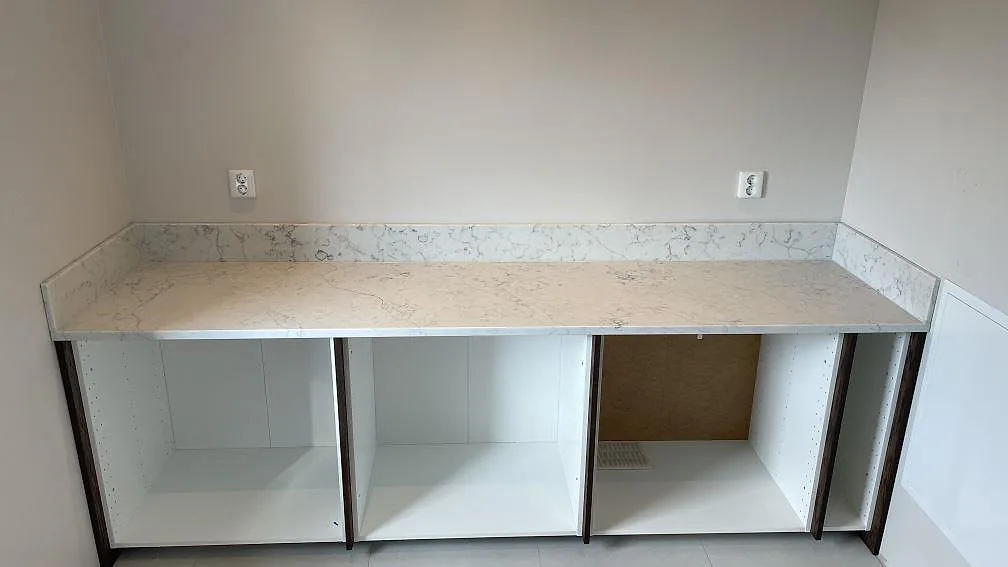 Köksbänkskiva i polerad Technistone Mystery White komposit med uppvikt stänkkant och öppna stommar i Rydsgård.