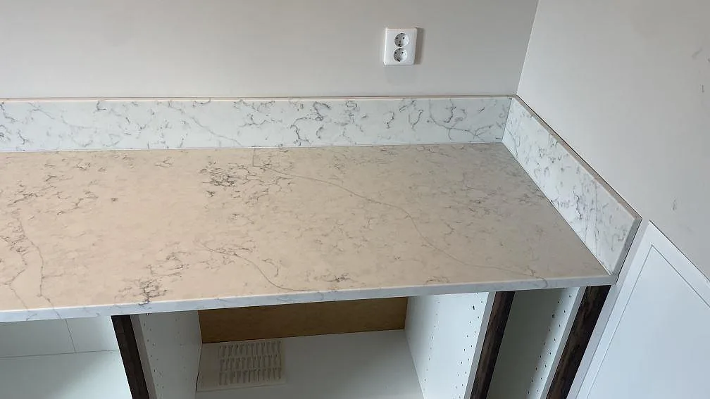 Polerad Technistone Mystery White kompositskiva med grå ådring och stänkkant vid höger vägg i Rydsgård.