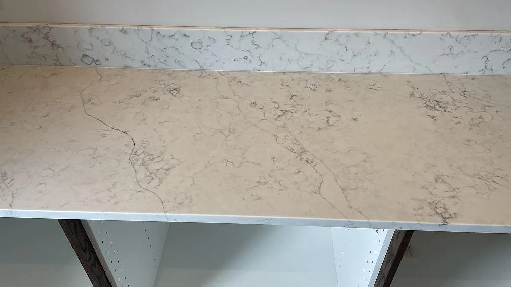 Närbild av polerad Technistone Mystery White kompositskiva med ljus yta, grå ådring och stänkkant i Rydsgård.
