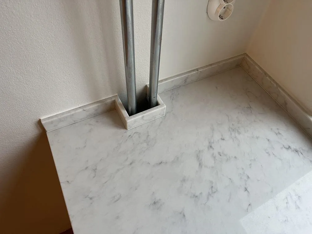 Närbild på halvöns polerade Technistone Mystery White kompositbänkskiva med ljus marmorerad ådring i Stockholm.