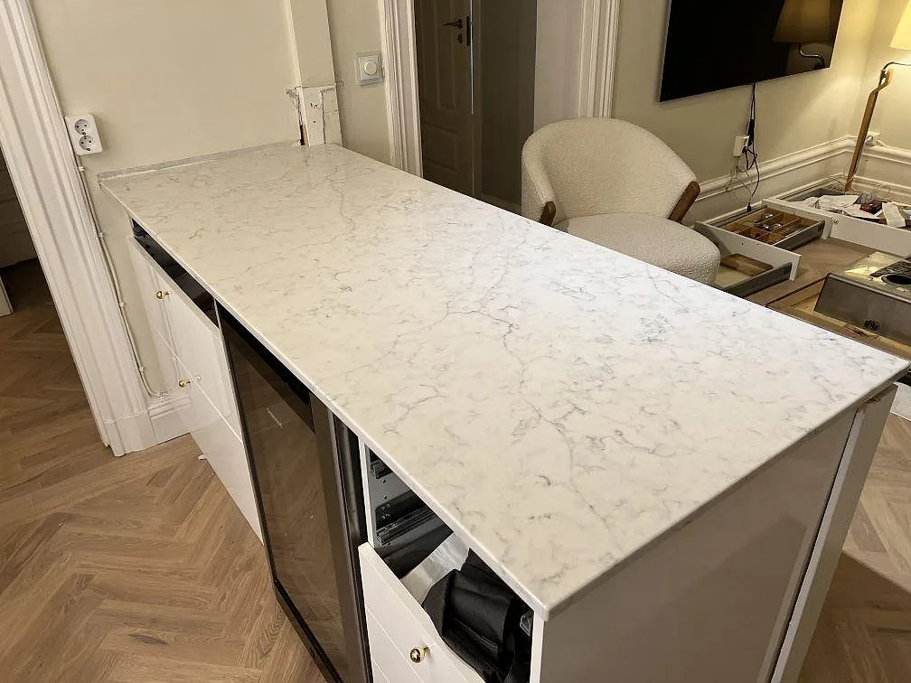 Närbild av köksö med 20 mm polerad Technistone Mystery White komposit och grå ådring i ett kök i Stockholm.