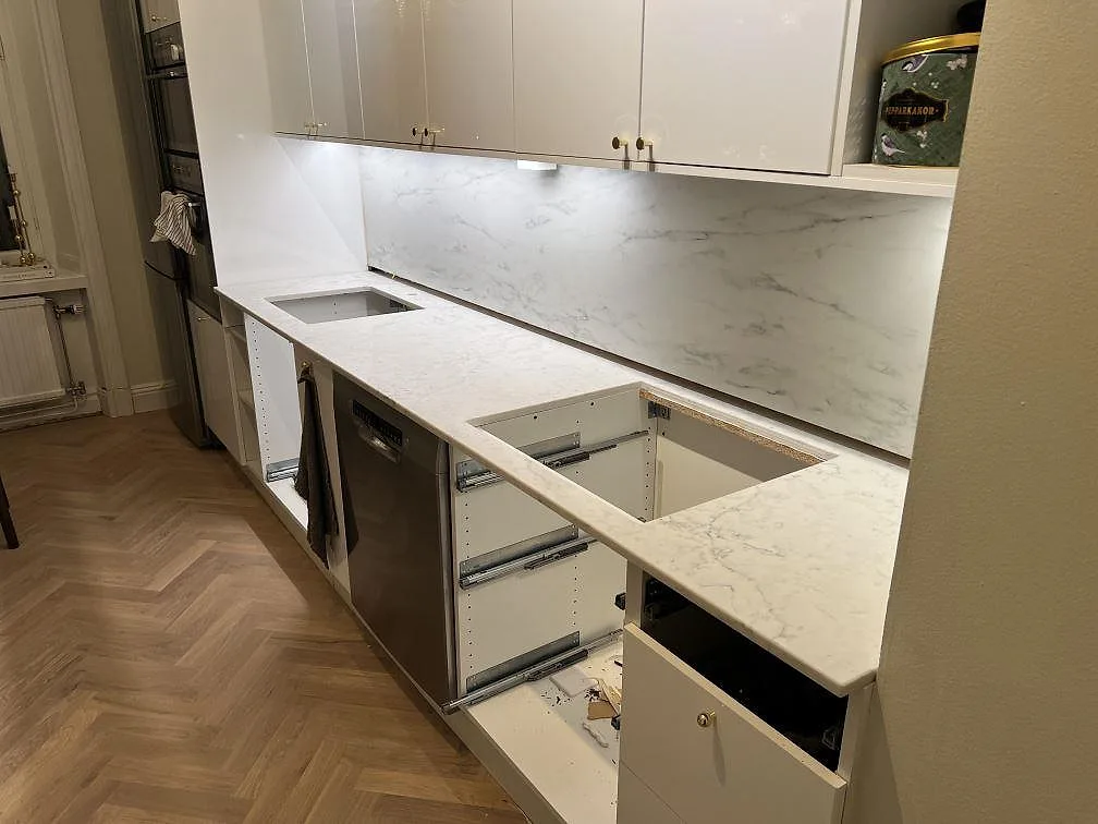 Polerad Technistone Mystery White komposit längs köksvägg med ljus ådring och synliga urtag i Stockholm.