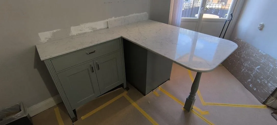 Polerad köksbänkskiva i Technistone Mystery White, vit komposit med grå ådring, på en halvö i Stockholm.