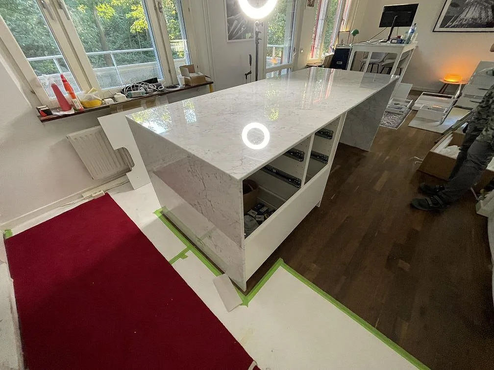 Polerad Technistone Mystery White på köksö med neddragen gavel, synlig ådring och monteringsskydd i Stockholm.