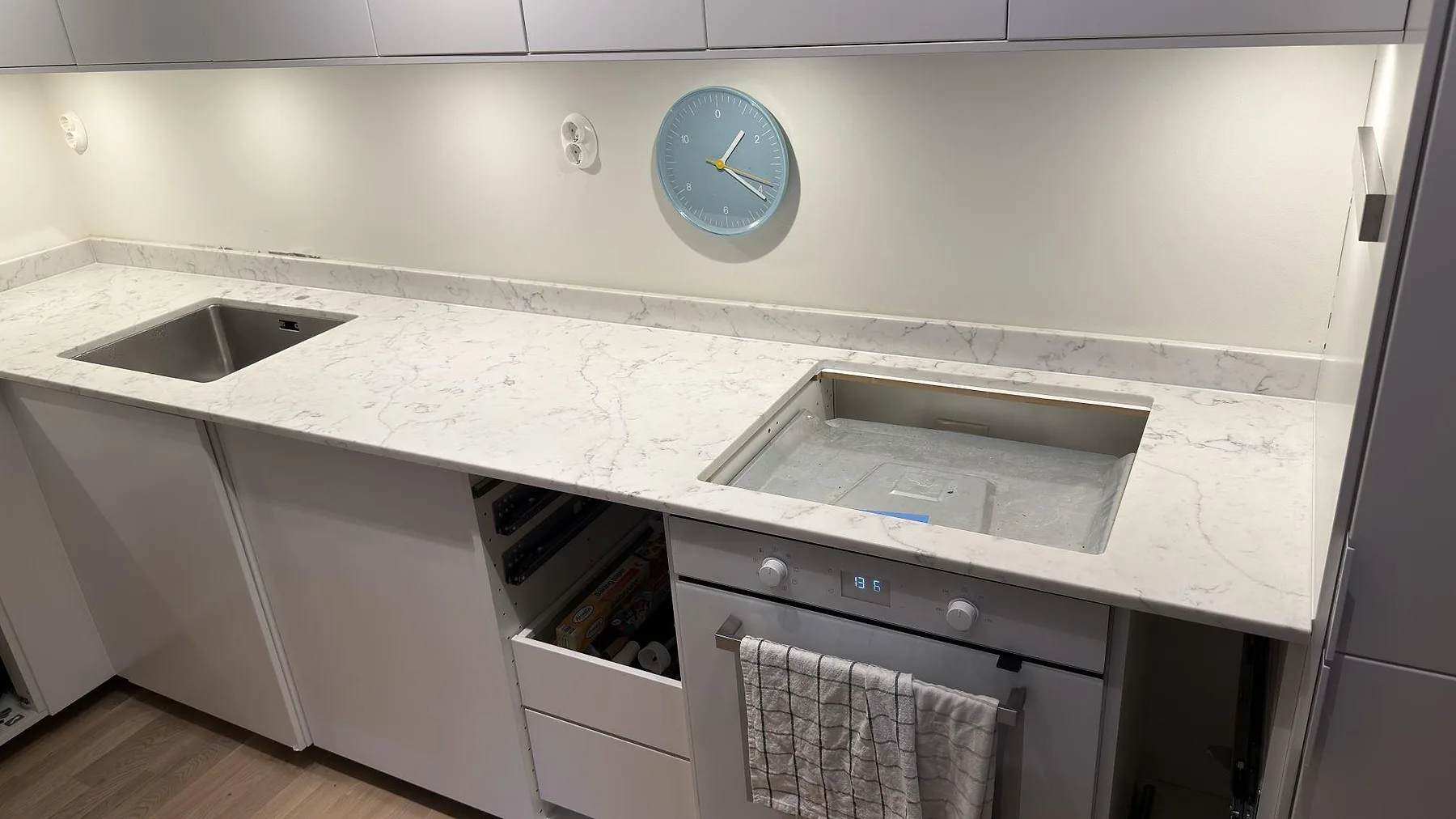 Närbild av polerad köksbänkskiva i Technistone Mystery White med rostfri diskho, hälluttag och ljus ådring i ett kök i Stockholm.