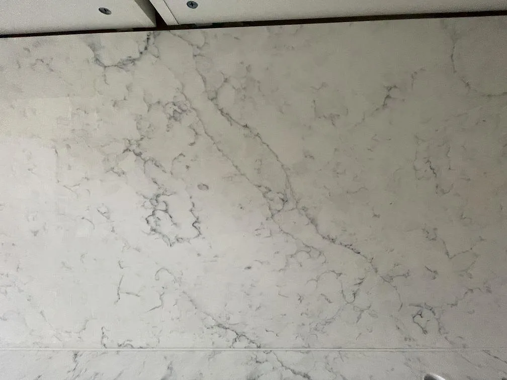 Närbild på den installerade bänkskivan i Technistone Mystery White, polerad yta med mjuk grå marmorlik ådring mot vit botten, i ett kök i Stockholm.