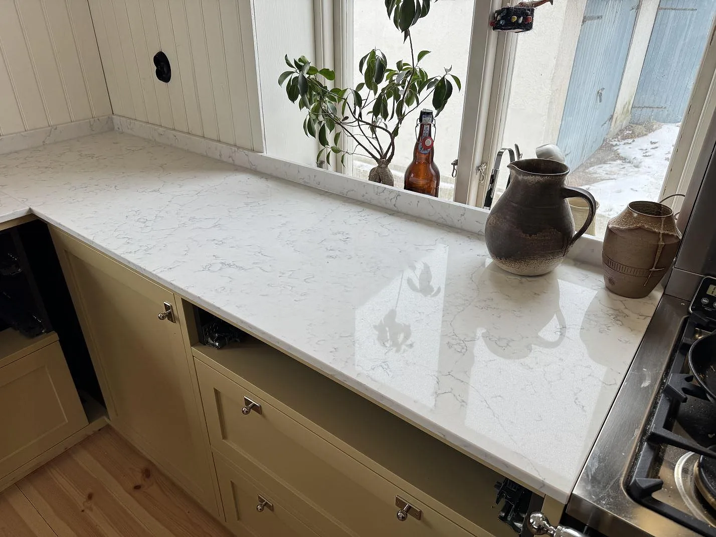Fönsterbänk och bänkskiva i Technistone Mystery White med krukväxter i ett pärlspontskök i Tygelsjö.