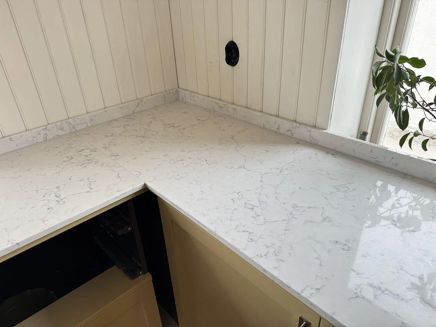 Ovanifrån på den polerade vita kvartskompositbänkskivan Technistone Mystery White i ett ljust kök i Tygelsjö.