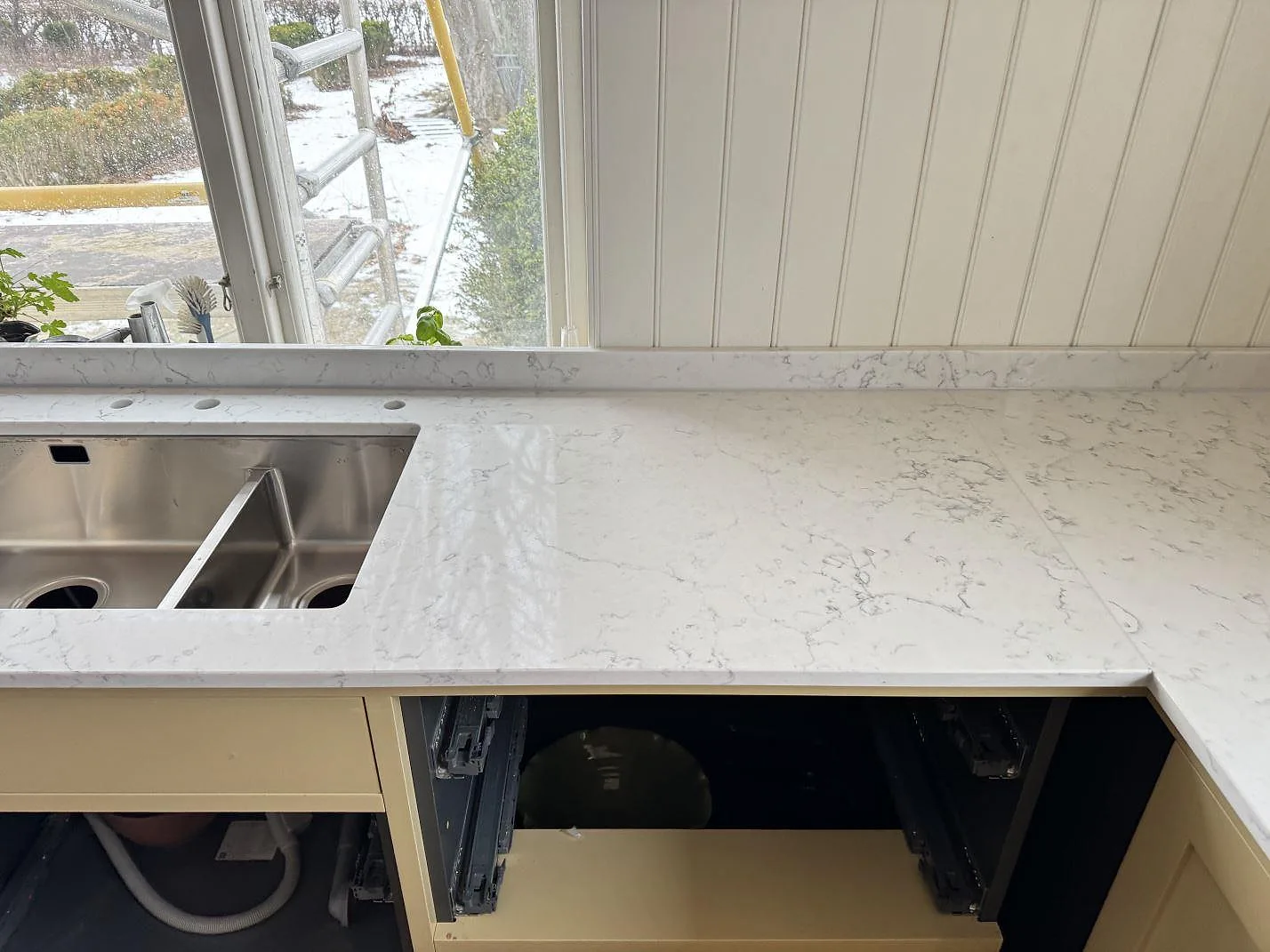Undermonterad rostfri dubbelho i polerad Technistone Mystery White bänkskiva med borrade tapphål i ett kök i Tygelsjö.