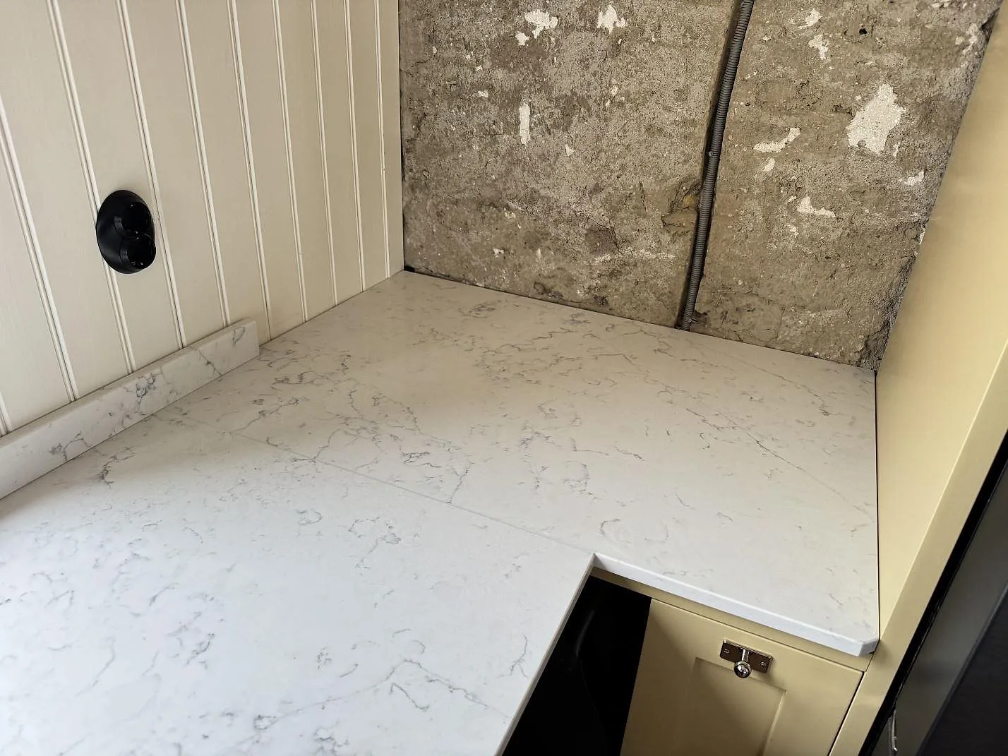 Vit Technistone Mystery White köksbänkskiva i hörnet med grå ådring och uppvikt stänkkant mot pärlspont i Tygelsjö.