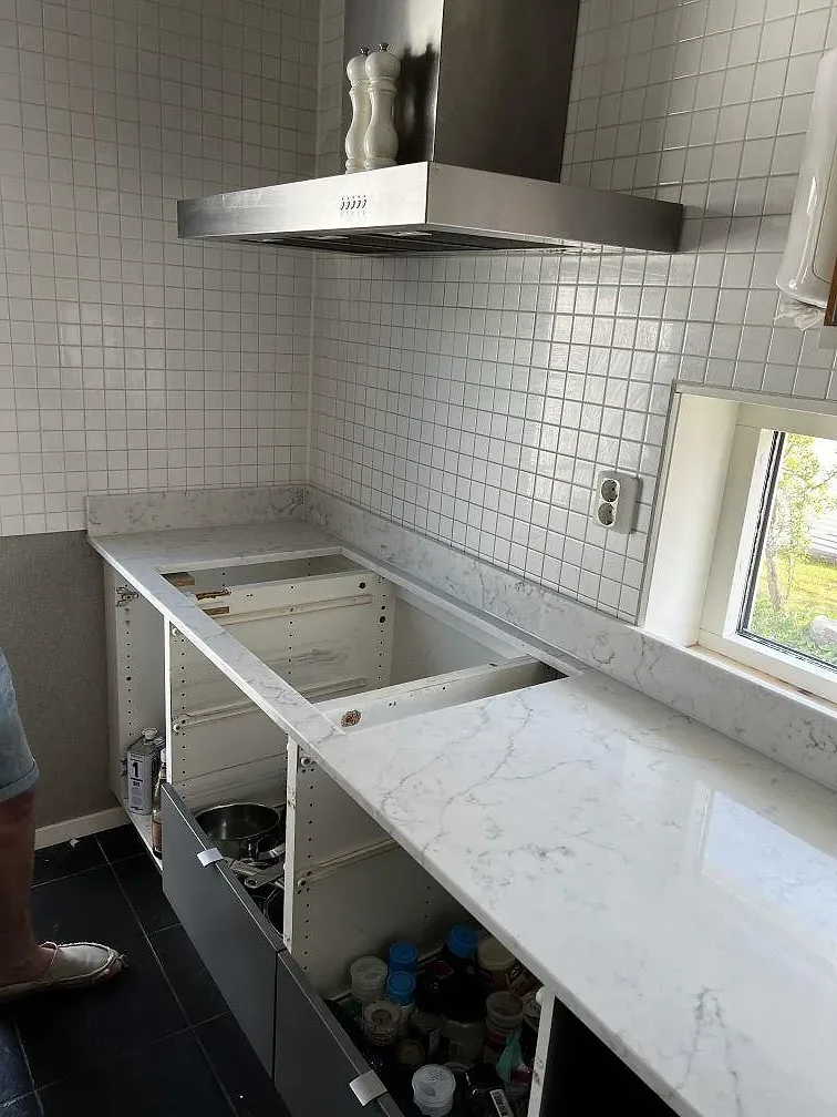 Köksbänkskiva i Technistone Mystery White, polerad, längs vitt kakel och öppna köksstommar i Uddevalla.