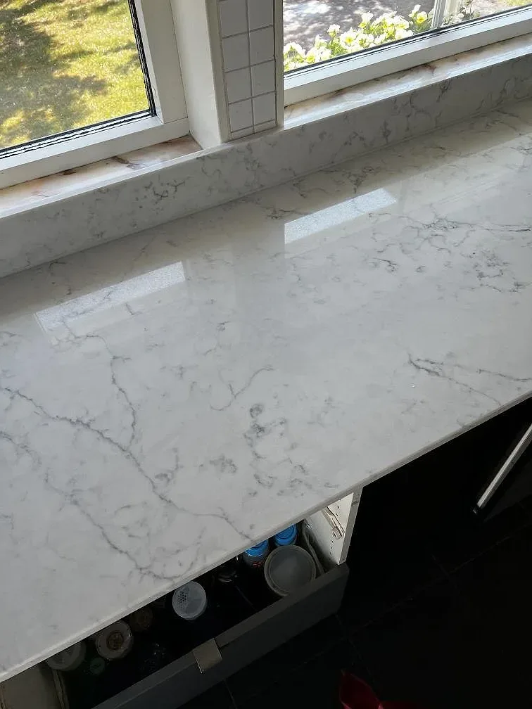Närbild på den polerade ytan i Technistone Mystery White komposit med ljus reflektion och grå ådring i Uddevalla.