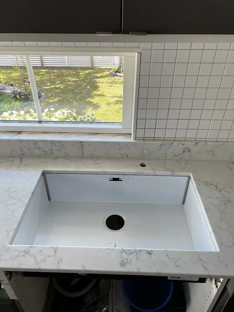 Närbild på diskhozonen i polerad Technistone Mystery White komposit med grå ådring i Uddevalla.