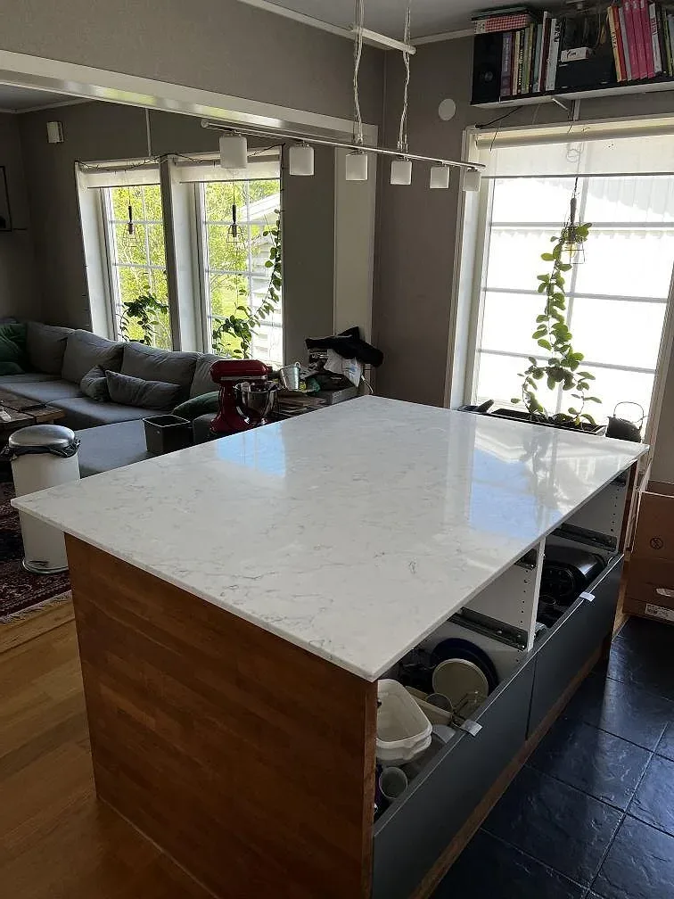 Köksbänkskiva i vit Technistone Mystery White komposit, polerad, monterad som lång arbetsyta och halvö i Uddevalla.
