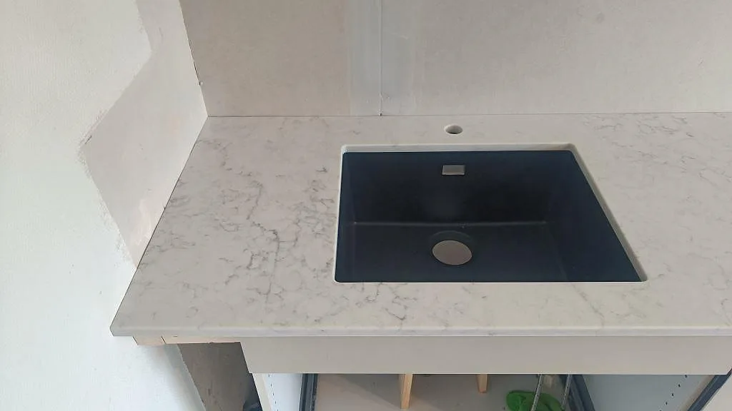 Diskbänk i polerad Technistone Mystery White komposit med svart underlimmad diskho och synlig marmorering i Västra Frölunda.
