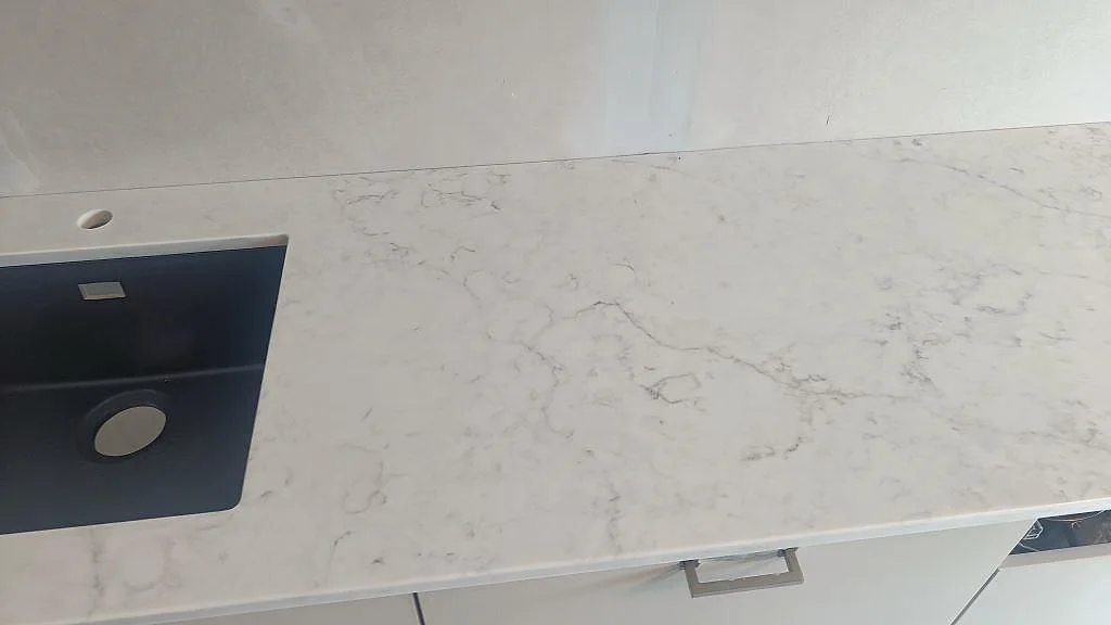 Närbild på köksbänkskiva i Technistone Mystery White komposit med svart diskho och ljusgrå ådring i Västra Frölunda.