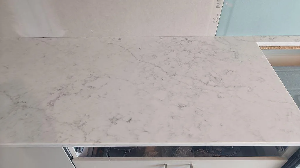 Detalj av polerad Technistone Mystery White kompositbänkskiva med ljusblå stänkpanel och hällkant i Västra Frölunda.