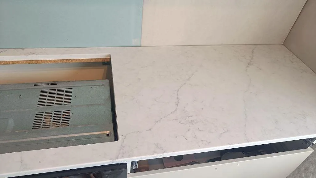 Köksbänkskiva i Technistone Mystery White komposit med hällöppning, vit skåpstomme och ljusblå väggskiva i Västra Frölunda.