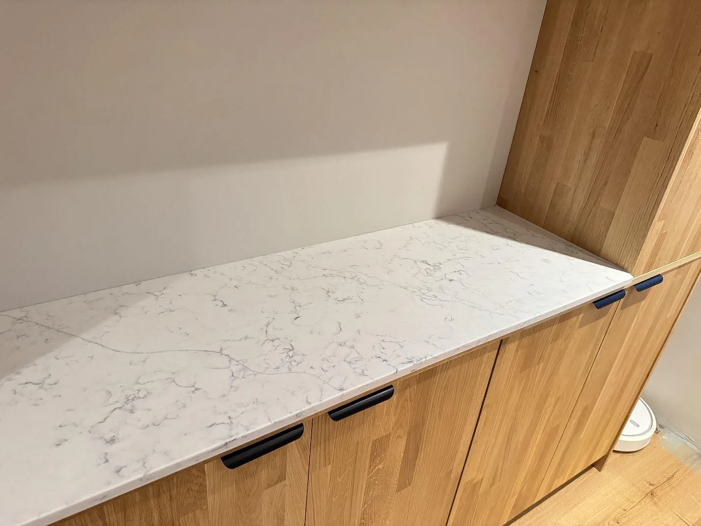 Sidobänk i Technistone Mystery White på träskåp, polerad vit kvartskomposit med marmorlik ådring i Veberöd.