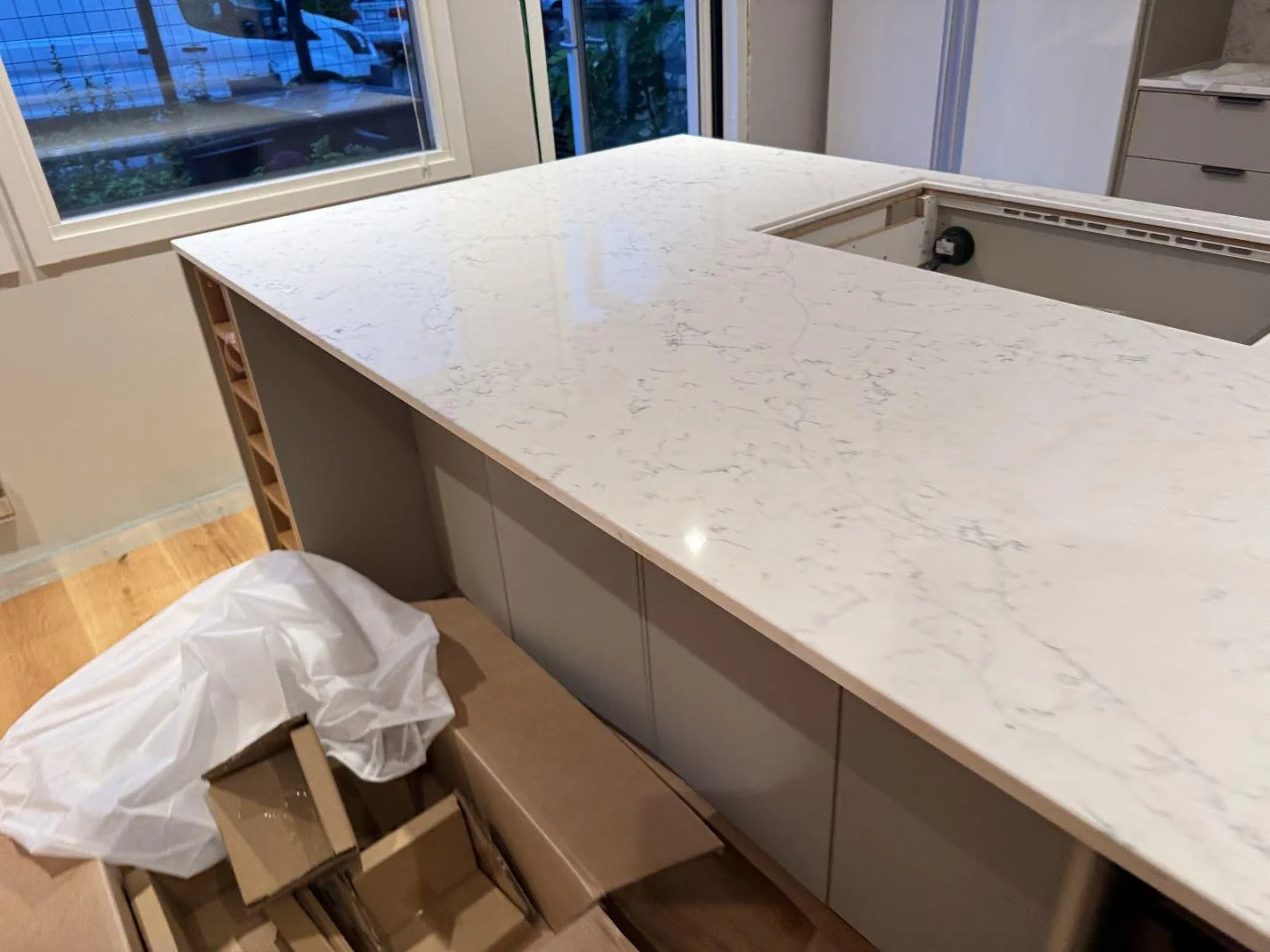 Polerad köksö i Technistone Mystery White med ljus ådring, monterad vid fönster i ett kök under montering i Veberöd.