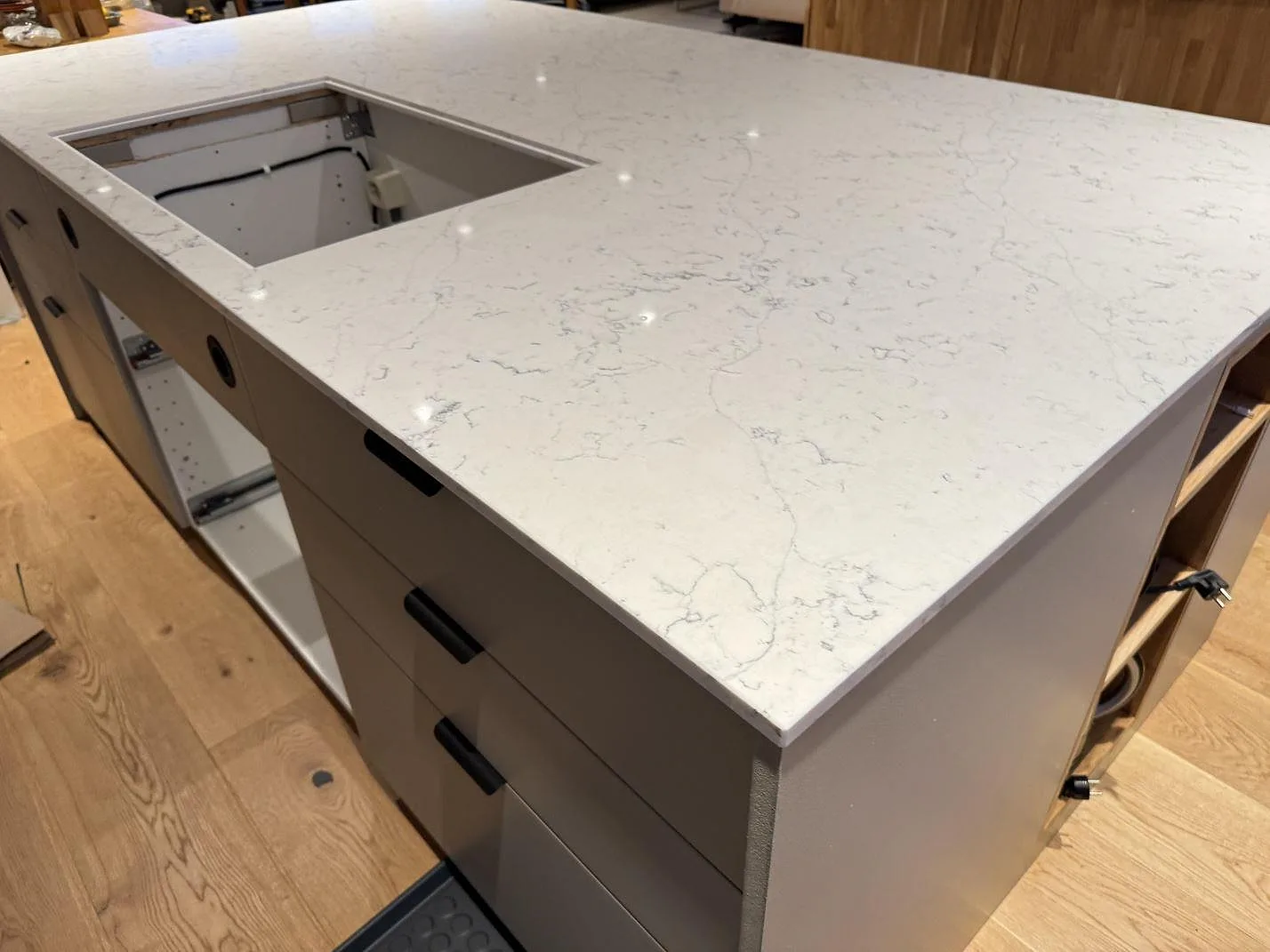 Köksö med bänkskiva i Technistone Mystery White, polerad 20 mm kvartskomposit och öppen hällutskärning i Veberöd.