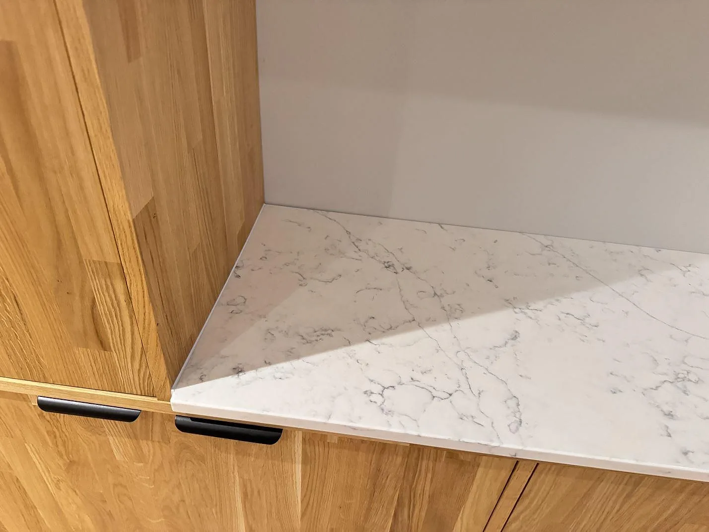 Detalj av 20 mm Technistone Mystery White på träinredning, polerad köksbänkskiva med ljus grå ådring i Veberöd.
